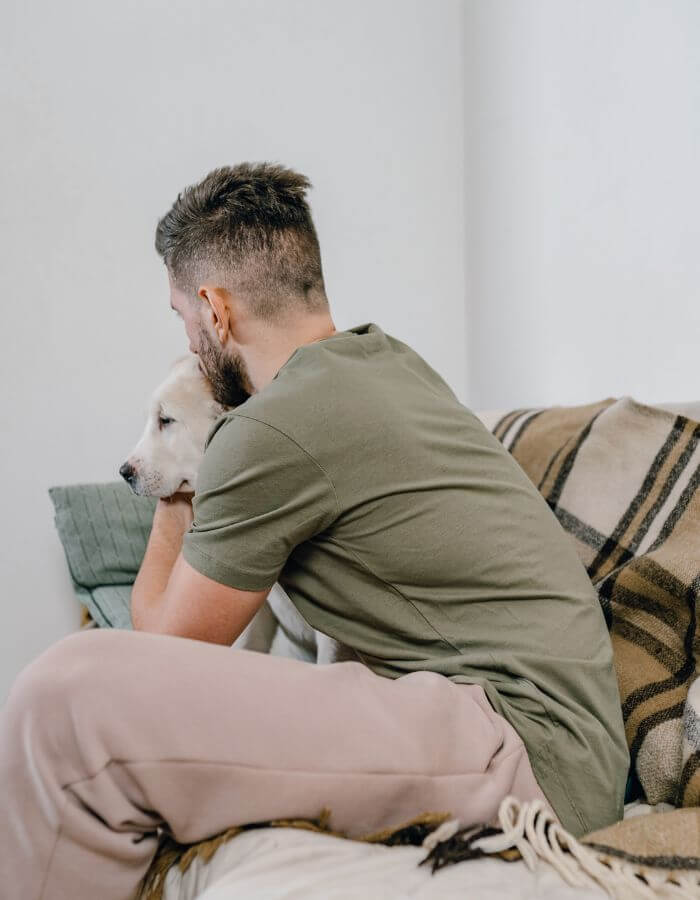 A person sitting on a couch and holding a dog close.