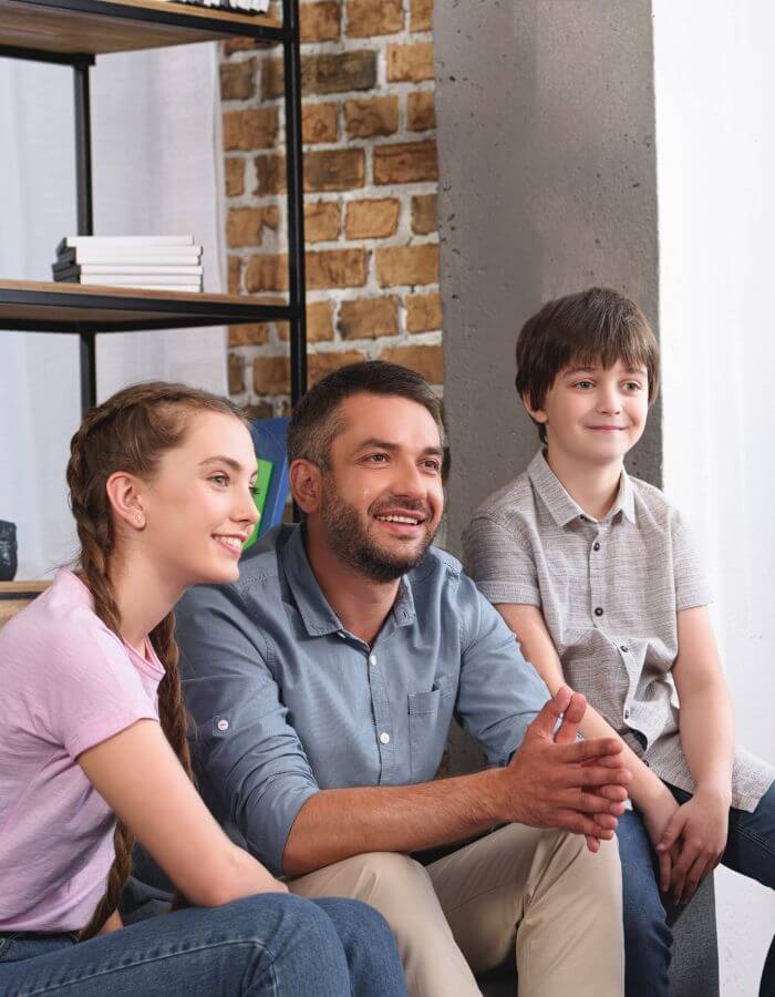 A parent sitting with two children during a family conversation.