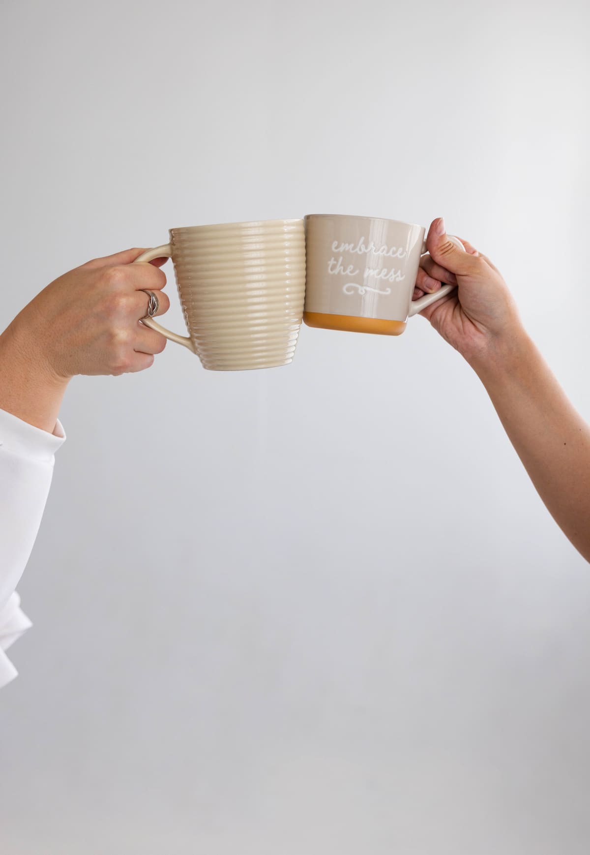 Two people raising coffee mugs in a friendly toast.